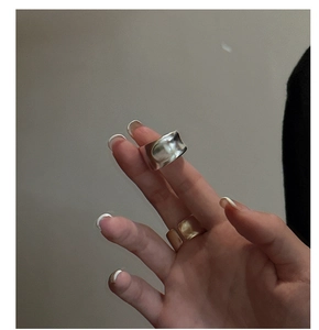 Close-up of matte silver irregular concave ring paired with a sleek gold minimalist band