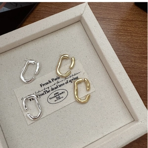 Detailed view of gold and silver irregular textured hoop earrings on a display tray