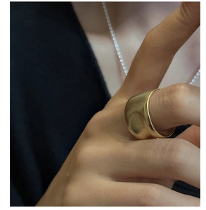 Detail of matte gold dome ring featuring a wide brushed surface worn on finger
