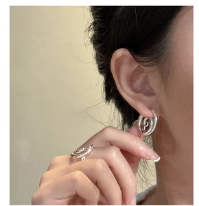 Detail of minimalist S925 sterling silver spiral ring and hoop earring on a model