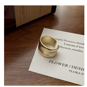 Close-up of matte gold S925 sterling silver ring with irregular wavy texture on a card