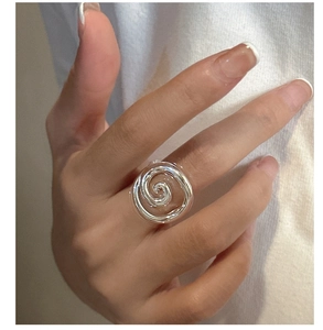 Detail view of a minimalist S925 silver spiral ring on model finger with sleek artistic texture