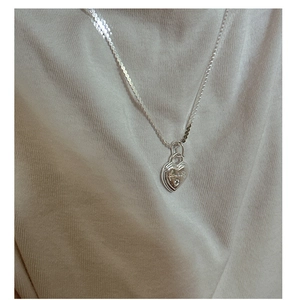 Vue détaillée d'un pendentif cœur en argent sterling S925 avec gravure sur un tricot doux