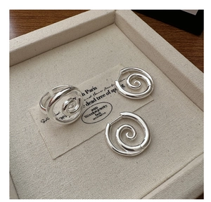 Detailed view of minimalist S925 sterling silver swirl ring and hoop earrings on a tray