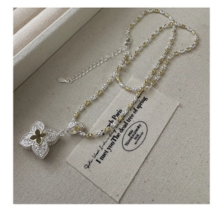 Macro detail of S925 silver necklace with two-tone floral pendant and engraved texture