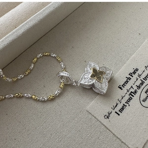 Macro shot of two-tone S925 silver clover pendant with vintage engraved relief texture