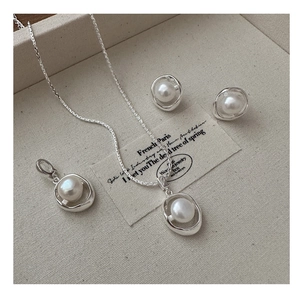Detailed view of S925 sterling silver jewelry set featuring elegant white pearls on fabric