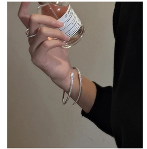 Details von silbernem Schlangenarmband und Ring mit Schuppentextur an einem Model