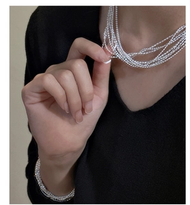 Macro shot of multi-layer silver beaded necklace and bracelet set with glossy finish