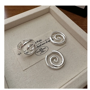 Detailed view of S925 sterling silver spiral ring and earrings set on a beige linen tray