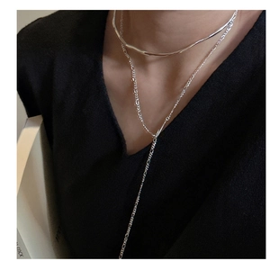 Detail of layered S925 silver liquid-style collar and Figaro Y-necklace on a model