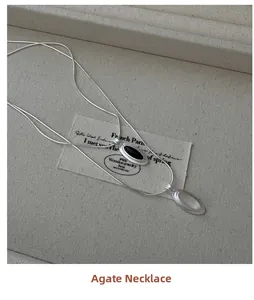 Detailed view of S925 silver snake chain with black agate teardrop pendant on linen tray