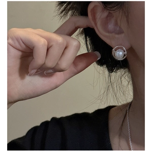 Detail view of a minimalist S925 sterling silver pearl earring worn by a female model