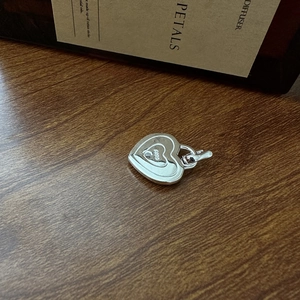 Pendentif double cœur en argent sterling S925 exposé sur une surface en bois naturel