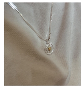Detail eines Vintage-Münzanhängers mit goldenem Herz an einer feinen Silberkette