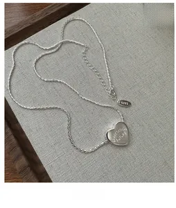 Macro shot of S925 sterling silver heart necklace featuring engraved letters and rope chain