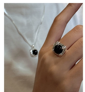 Detailed view of S925 silver ring and necklace set with black onyx and hammered metal texture