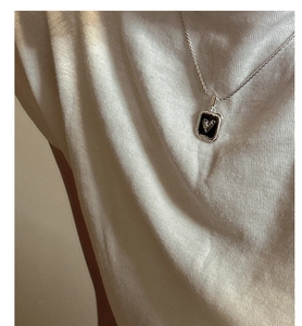Detail of S925 sterling silver necklace with retro black heart pendant on a woman