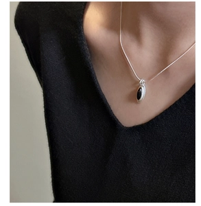 Close-up of S925 silver necklace with black teardrop agate pendant worn on a collarbone