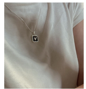 Close-up of S925 silver heart necklace with black enamel pendant on a knitted sweater