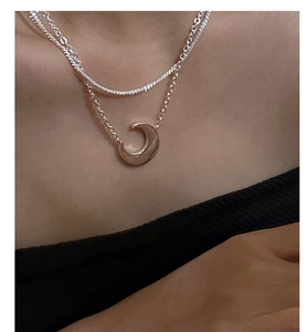 Detail of a minimalist layered S925 sterling silver necklace with a crescent moon pendant