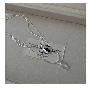 Detail view of oval teardrop agate pendants on silver snake chains in a jewelry box