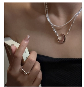 Macro detail of silver double-layer moon necklace and matching geometric ring on a model