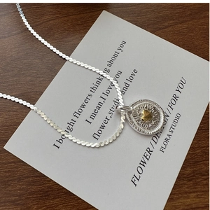 Makro-Detail der S925 Sterling Silber Kette mit goldenem Herzanhänger auf weißer Karte