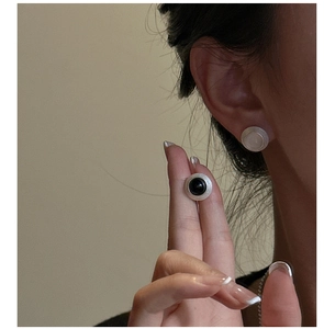Détail de boucles d'oreilles argentées mates avec texture brossée et incrustation ronde