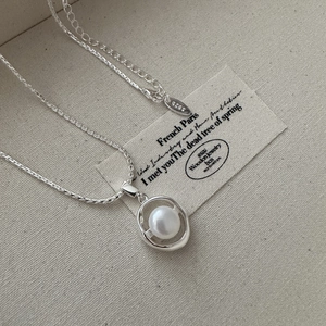 Elegant S925 sterling silver necklace with oval pearl pendant on a beige canvas background