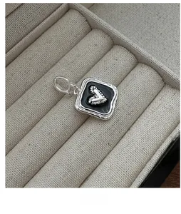 Detailed view of a vintage square silver heart pendant with black enamel inlay and swivel clasp