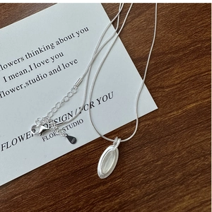 Macro shot of S925 silver teardrop opal necklace on wooden background with art card