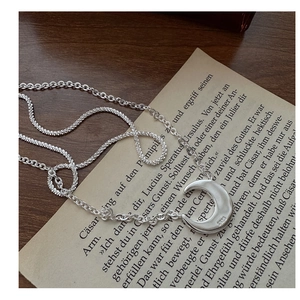 Macro view of S925 sterling silver moon pendant with double layered mixed chain textures