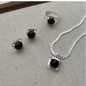 Detailed set of black agate jewelry including ring, necklace and earrings on linen background