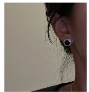 Détail d'une boucle d'oreille en argent mat avec pierre noire portée à l'oreille