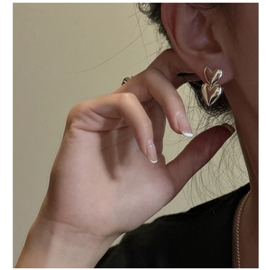 Close-up of polished S925 sterling silver double heart stud earrings on ear model