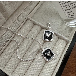 Macro shot of French vintage square black heart pendant in a beige velvet jewelry box