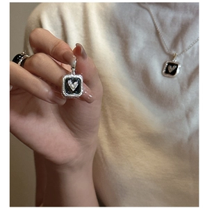 Macro view of vintage S925 silver square pendant with black enamel heart detail