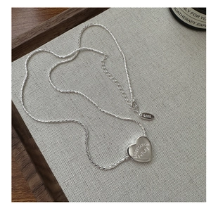 Macro shot of S925 silver heart necklace featuring engraved Expectation Future text