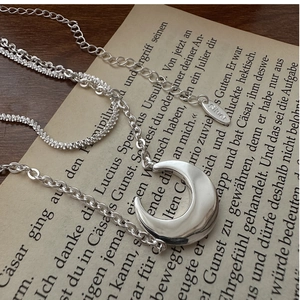 Detail of S925 sterling silver double-layer crescent moon necklace on a vintage book
