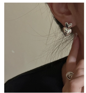Detailed close-up of double heart-shaped silver earrings worn by model for a trendy look