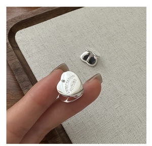 Close-up of S925 sterling silver heart earrings with EXPECTATION FUTURE engraved texture
