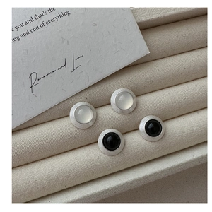 Détail de boucles d'oreilles en argent mat avec texture brossée et incrustations bicolores