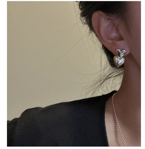 Detail of silver double heart studs with mirror finish on a female model