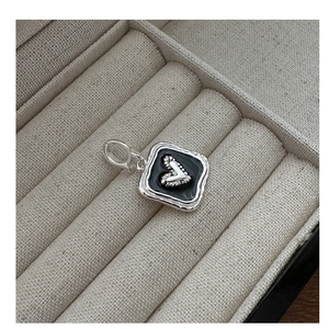 Macro detail of a vintage S925 silver square pendant with black enamel and a small heart