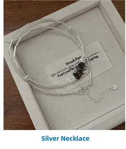 Macro view of S925 silver necklace with brown stone beads and engraved heart charm