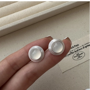Détail de boucles d'oreilles vintage en argent S925 avec pierres rondes mates aux doigts