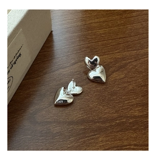 Detailed close-up of S925 sterling silver double heart stud earrings on wooden background