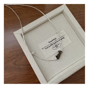 Detail of S925 sterling silver chain with natural brown stone beads on wooden tray