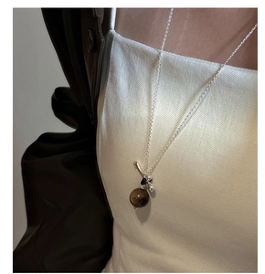 Détail d'un collier en argent S925 avec pendentif en œil de tigre marron sur un mannequin